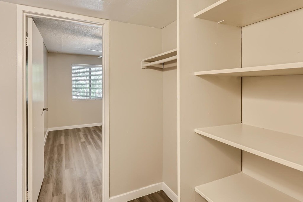 A white closet with shelves and a door open to a hallway.