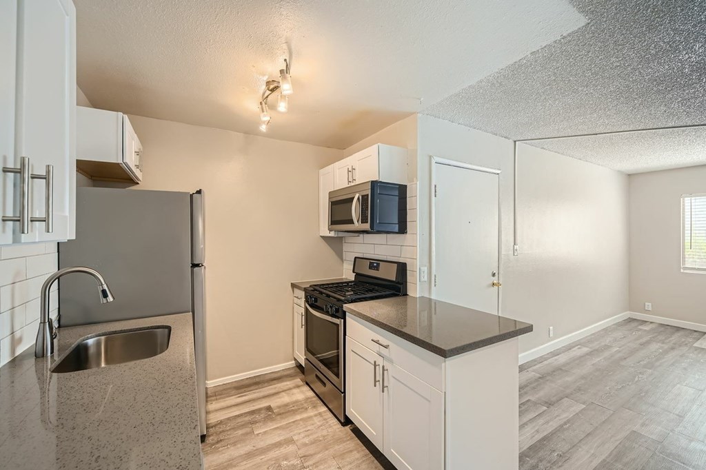 A kitchen with a stainless steel refrigerator, microwave, and oven.