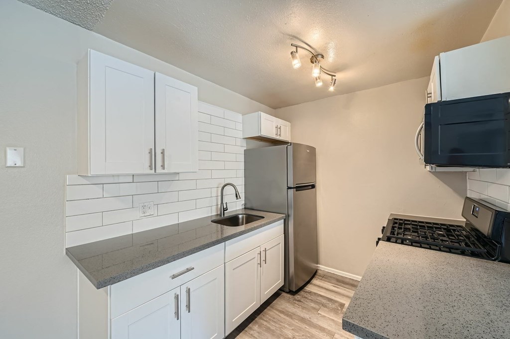 A kitchen with white cabinets and a grey countertop.