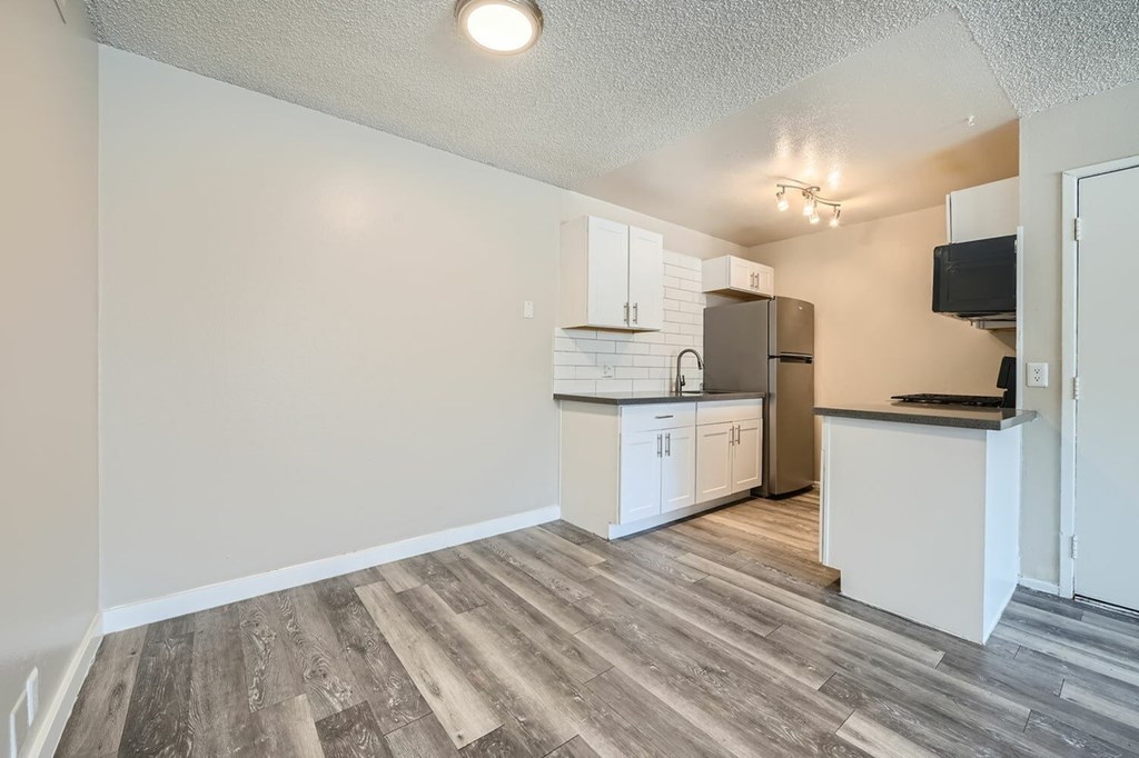 A kitchen with white cabinets and a wooden floor.