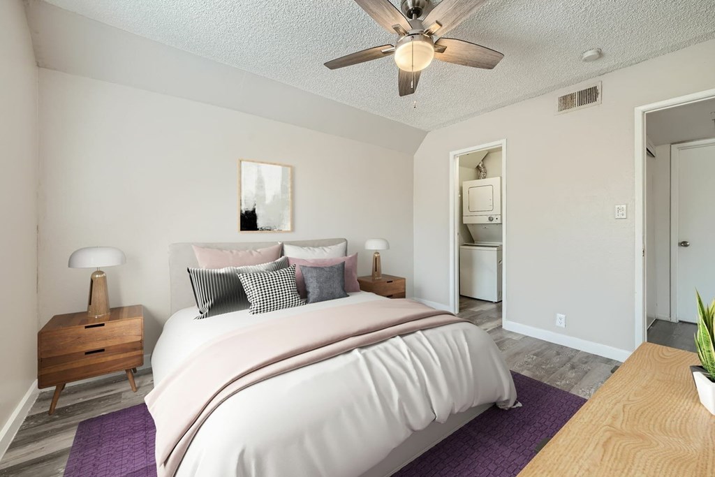 A bedroom with a bed, nightstand, and a ceiling fan.