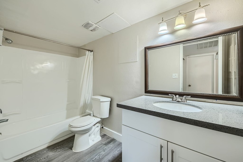 A white bathroom with a toilet, sink, and mirror.