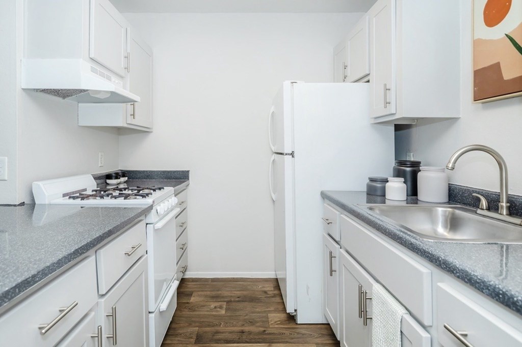 A kitchen with white cabinets and a grey countertop.