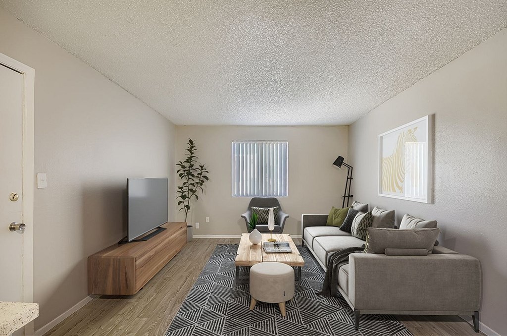 A living room with a rug, a couch, a table, and a ceiling fan.