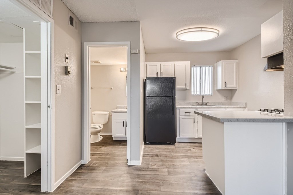 A kitchen with a black fridge and white cabinets.