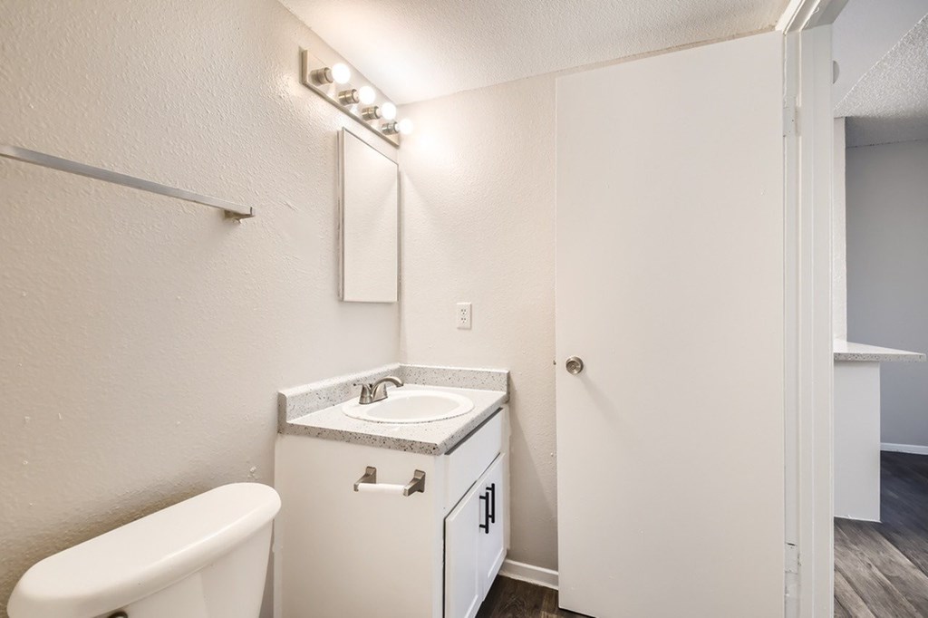 A white bathroom with a toilet, sink, and mirror.