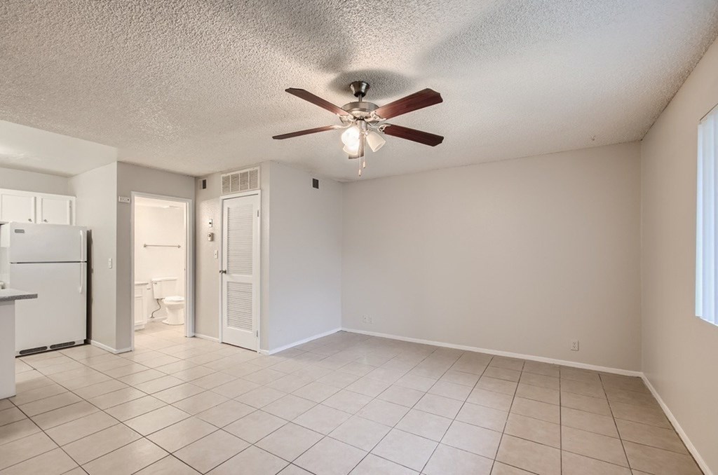 A spacious room with a ceiling fan and tile flooring.