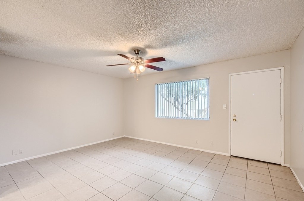 A room with a ceiling fan and a window with blinds.