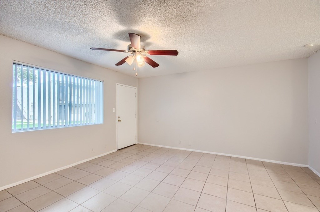 A room with a ceiling fan and a window with blinds.
