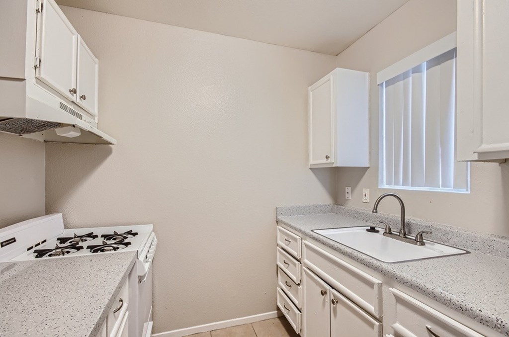 A kitchen with a white stove and cabinets.