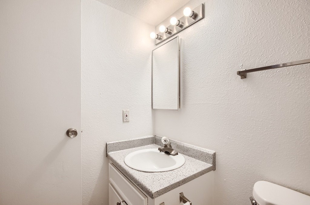 A bathroom with a sink, mirror, and lights.