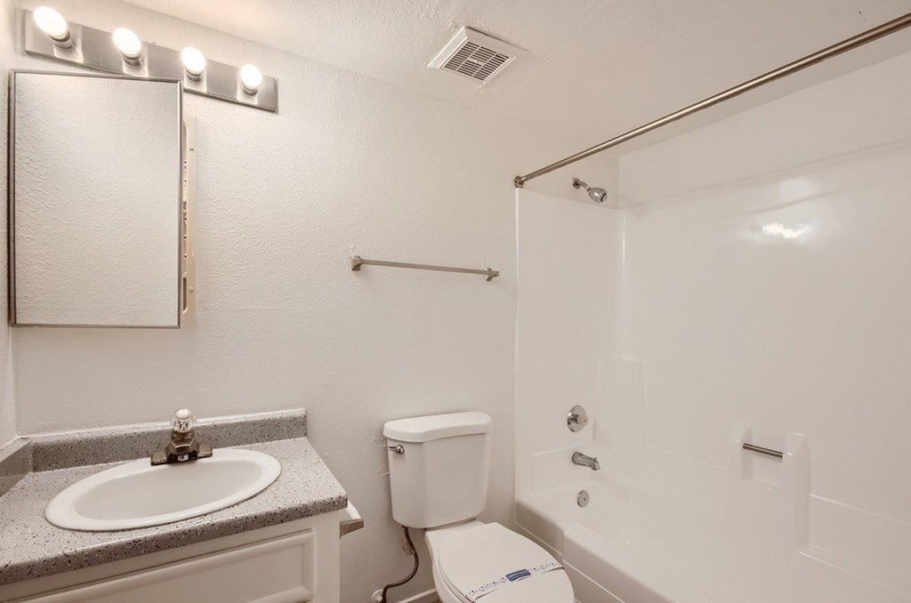A white bathroom with a sink, toilet, and shower.