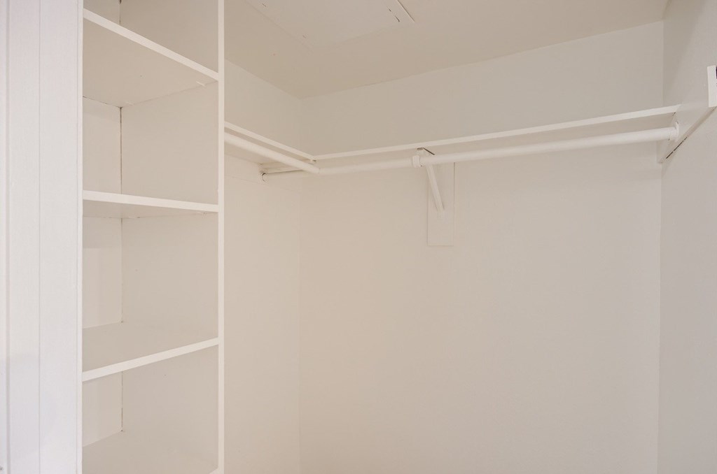 A white closet with shelves and a hanging rail.