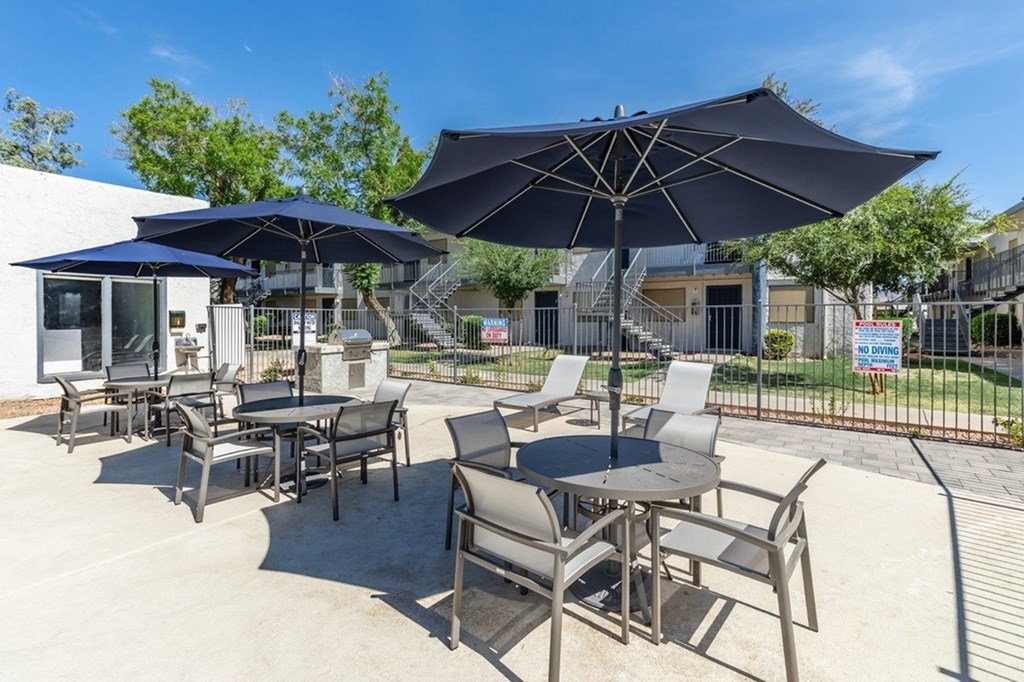 A patio with chairs and tables under umbrellas.