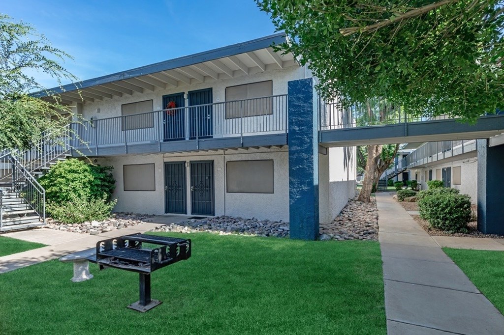 A black bench sits on a green lawn in front of a blue and white building.