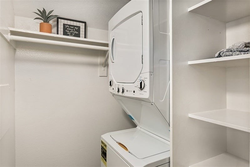 A small white refrigerator with a plant on top of the shelf.