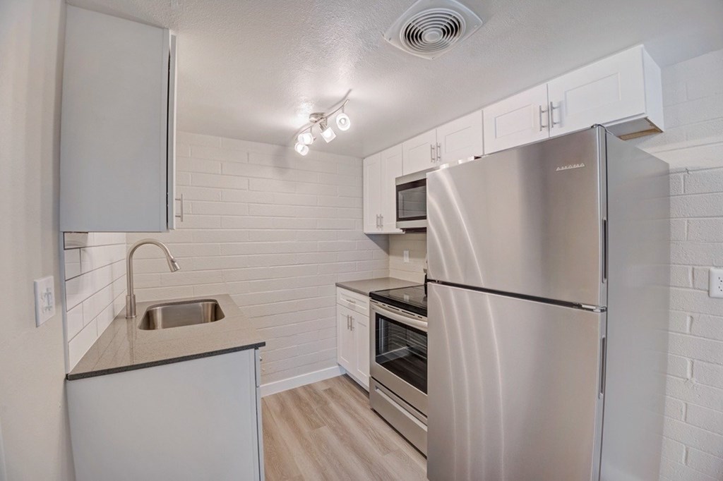 A kitchen with a stainless steel refrigerator, sink, and oven.