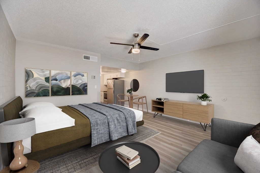 A bedroom with a bed, a couch, a ceiling fan, and a painting on the wall.