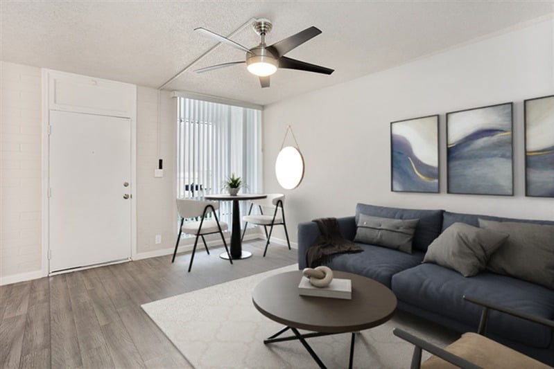 A living room with a blue couch and a ceiling fan.