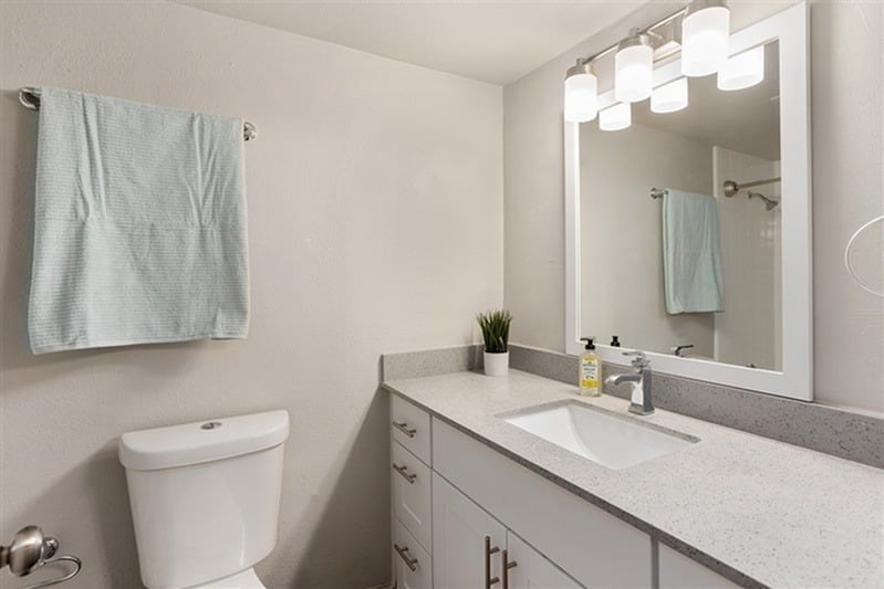 A bathroom with a white toilet, a sink, a mirror, and a towel hanging on the wall.