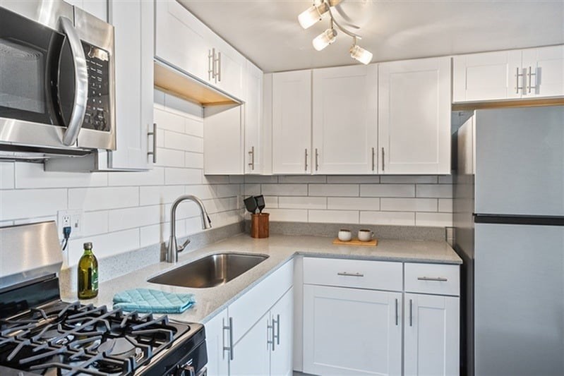 A kitchen with white cabinets and a stove top oven.