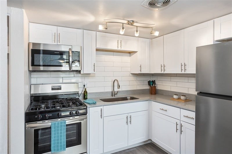 A modern kitchen with white cabinets and stainless steel appliances.
