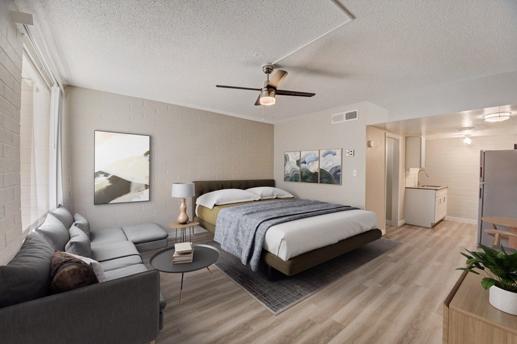 A bedroom with a bed, couch, and ceiling fan.