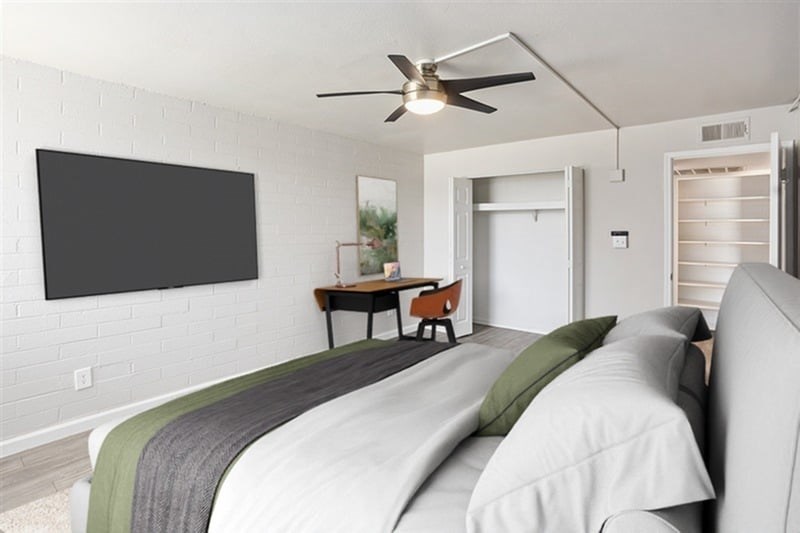 A bedroom with a bed, a chair, and a television mounted on the wall.