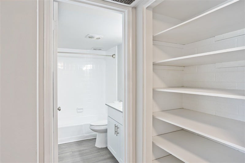 A white bathroom with a toilet and a white cabinet.