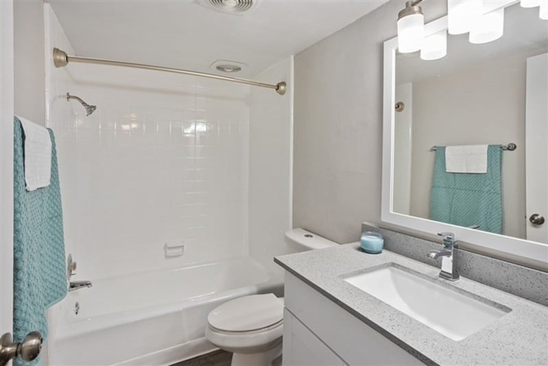 A bathroom with a white toilet, a white sink, a white bathtub, and a white mirror.