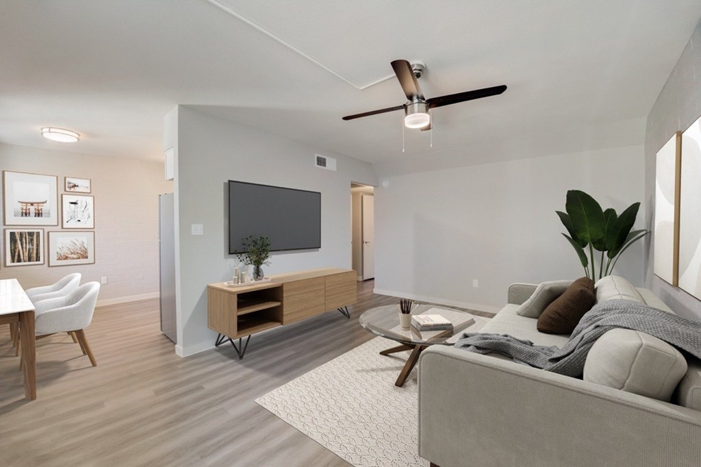 A modern living room with a grey sofa, a wooden coffee table, and a flat-screen TV mounted on the wall.