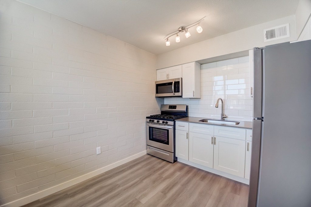 A kitchen with white cabinets and a stainless steel refrigerator.