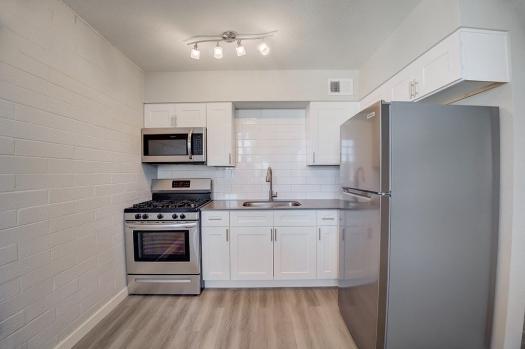 A kitchen with a stove, microwave, and refrigerator.