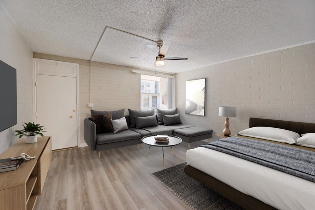 A bedroom with a bed, couch, and coffee table.