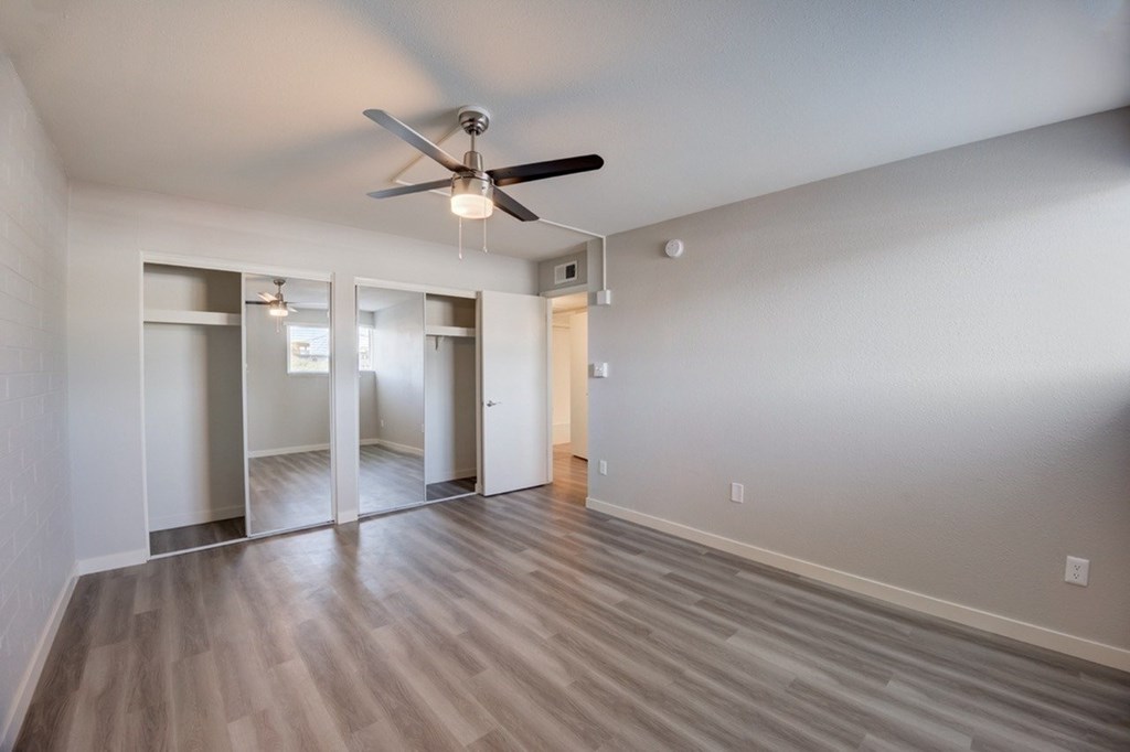 A room with a ceiling fan and mirrors on the wall.