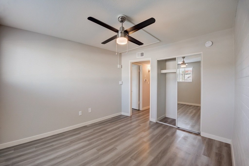 A room with a ceiling fan and wooden flooring.
