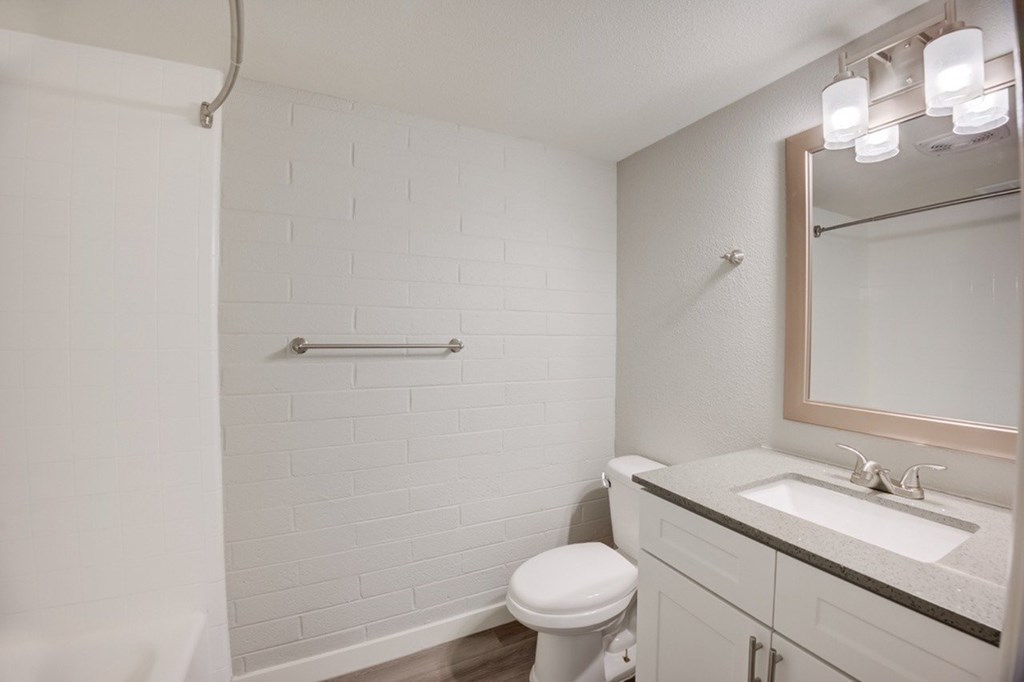 A white bathroom with a toilet, sink, and mirror.