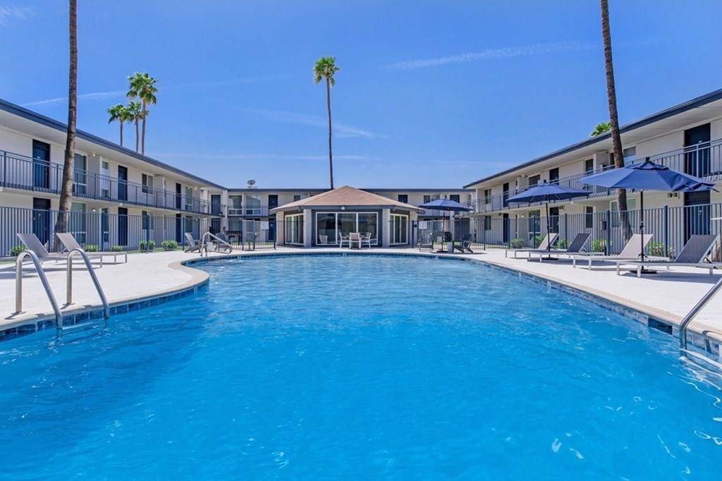 A large swimming pool in a resort with palm trees.