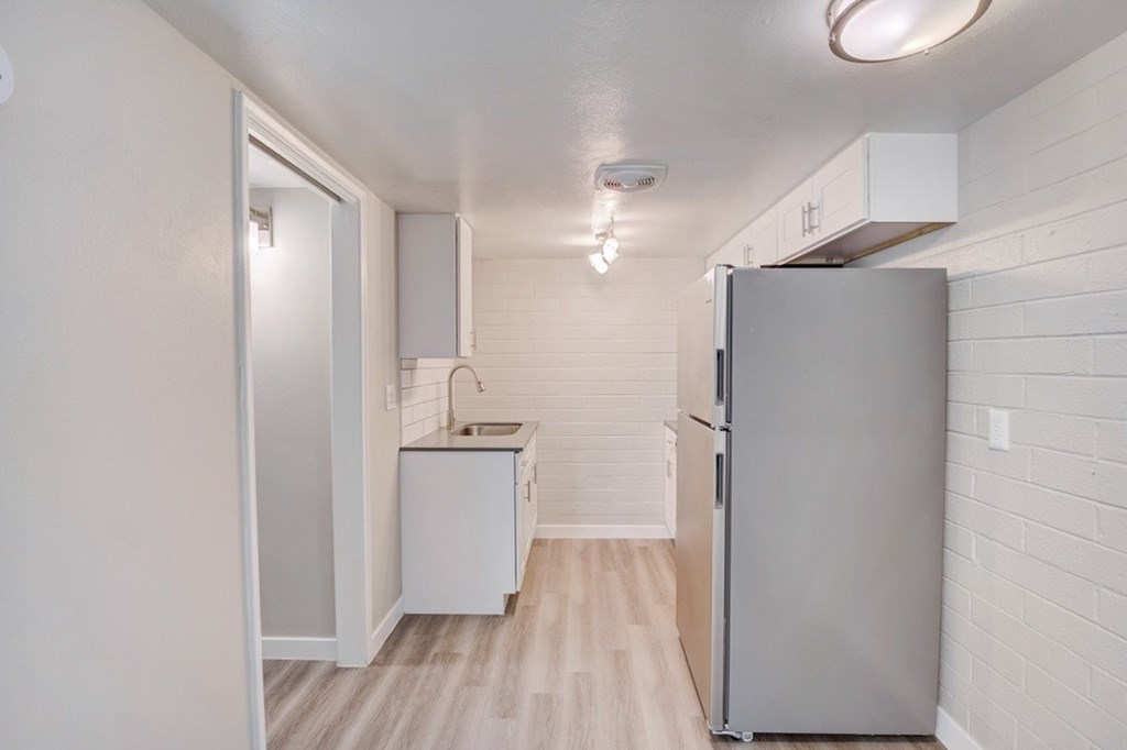 A small kitchen with a refrigerator, sink, and cabinet.