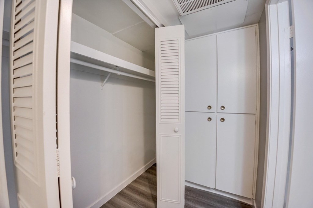 A white closet with a shelf and a door.