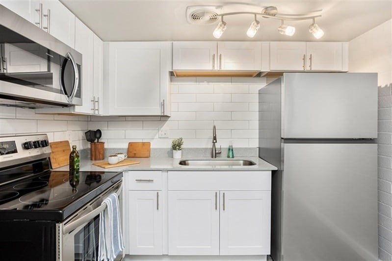A modern kitchen with white cabinets and stainless steel appliances.