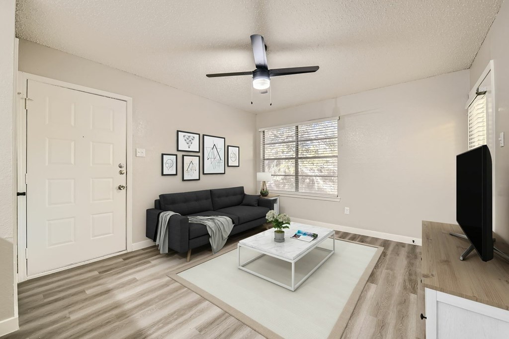 A living room with a black couch, a white coffee table, and a ceiling fan.