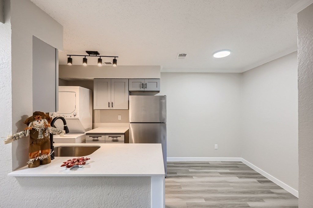 A kitchen with a white countertop and a stainless steel refrigerator.