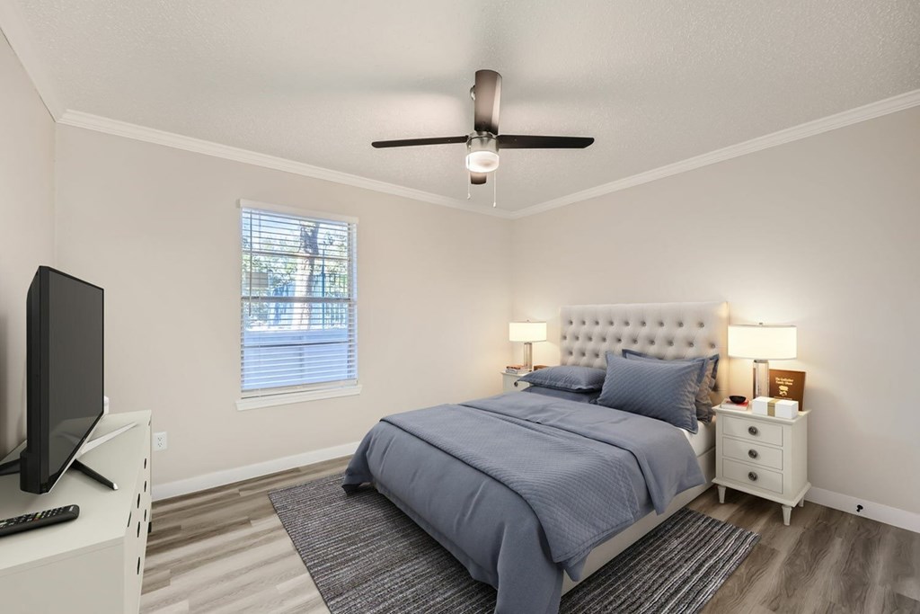 A bedroom with a bed, nightstand, and television.