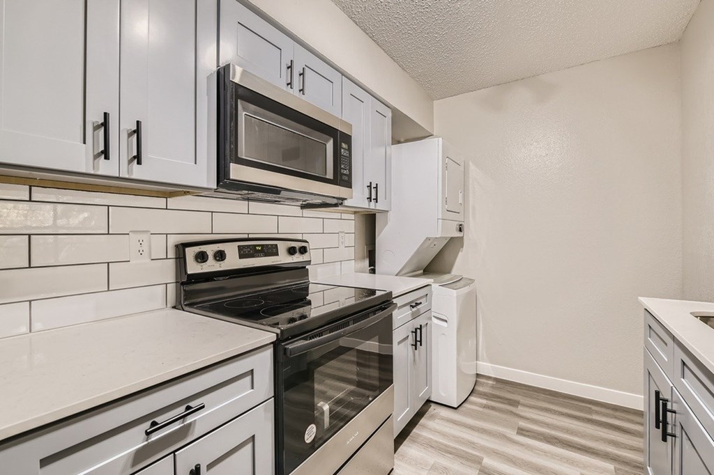 A kitchen with white cabinets and black appliances.