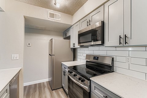 A kitchen with white cabinets and black appliances.