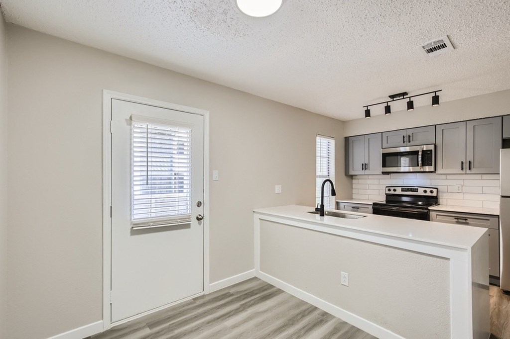 A kitchen with a white countertop and a sink.