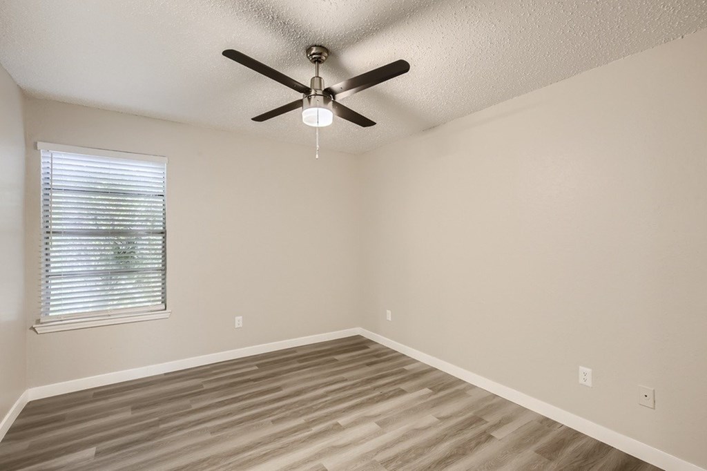 A room with a ceiling fan and a window with blinds.
