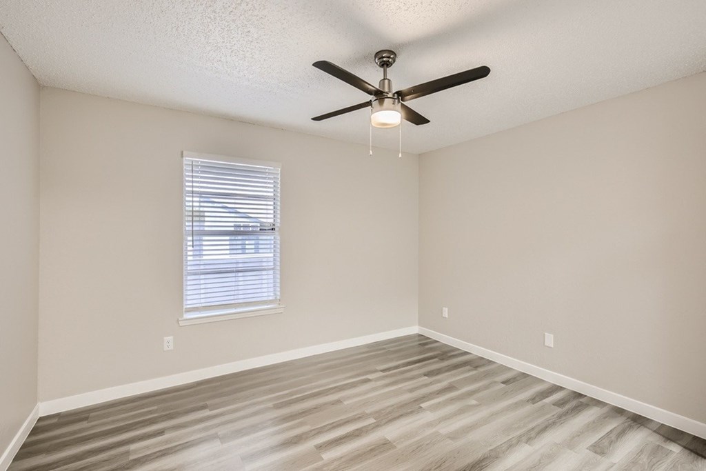 A room with a ceiling fan and a window with blinds.