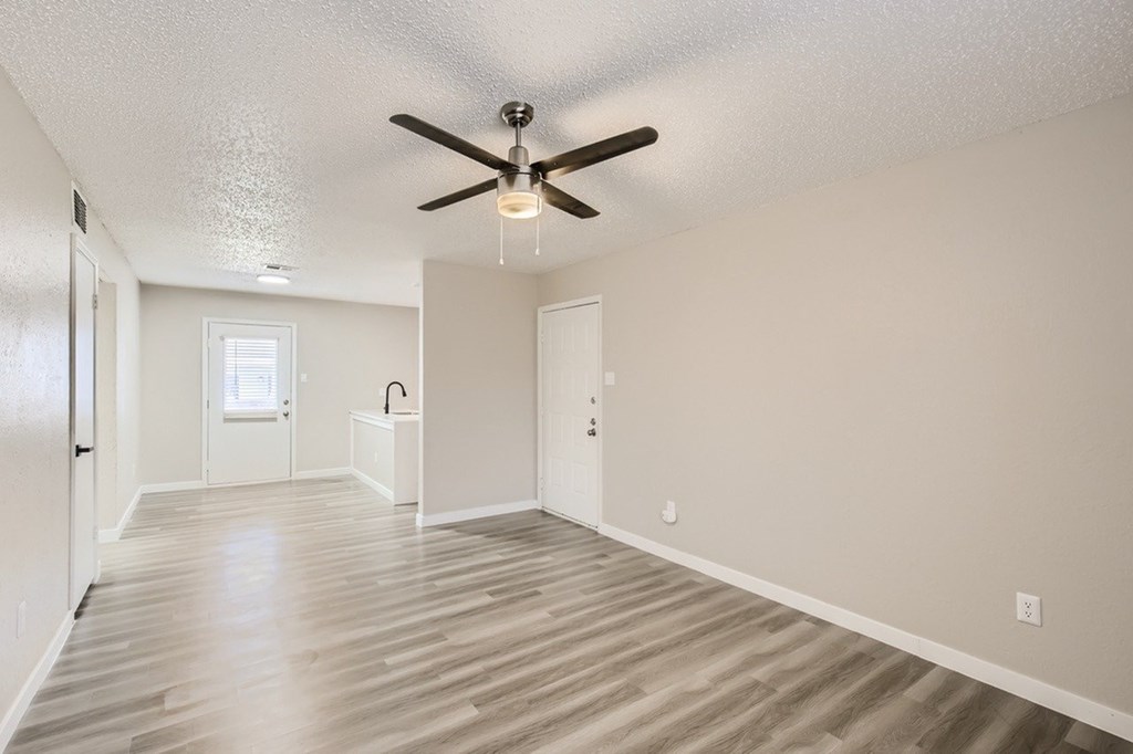A room with a ceiling fan and wooden flooring.